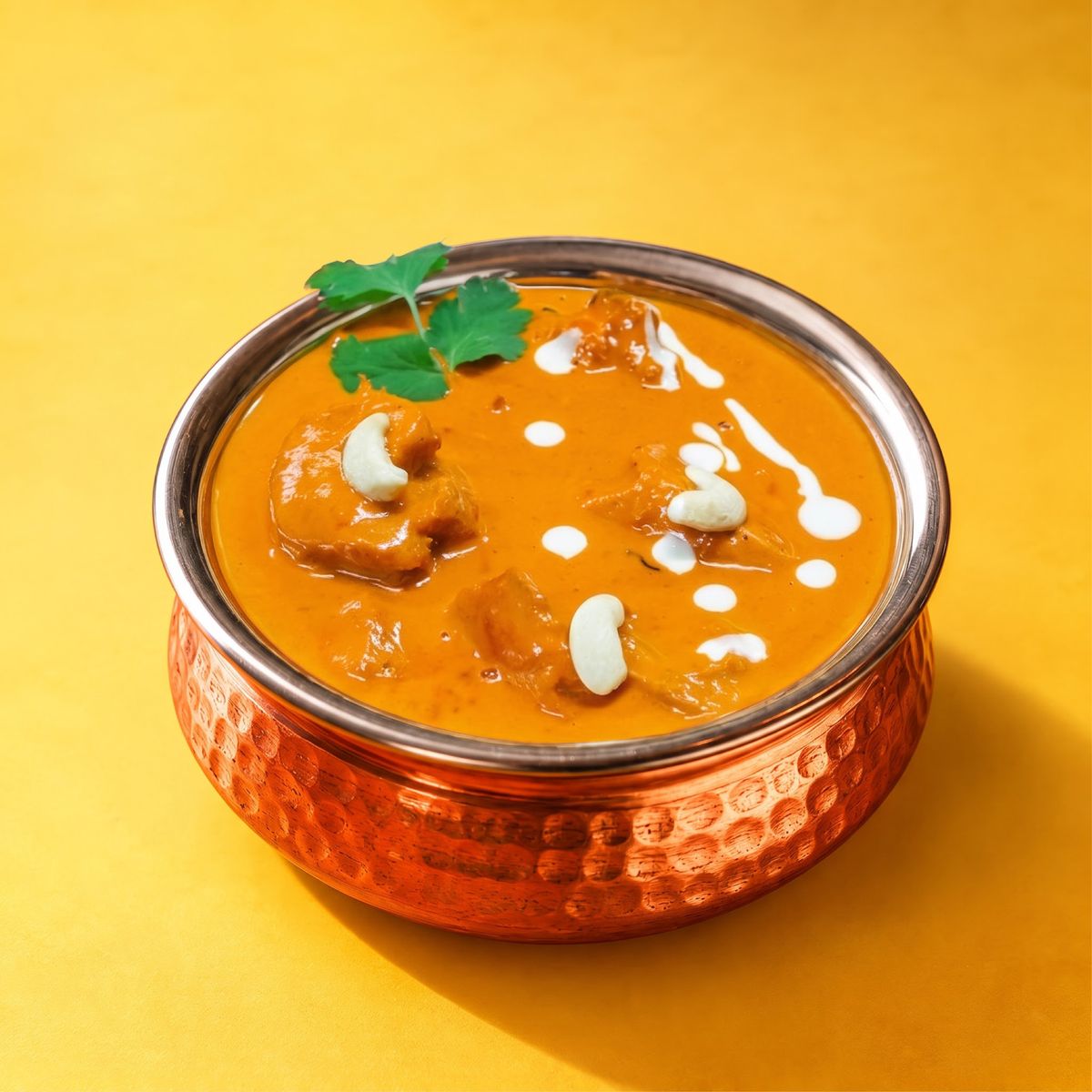 Touch of India butter chicken with a swirl of cream in a copper bowl