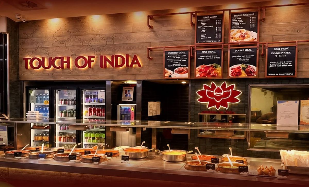 Touch of India food court counter with fresh curries in copper pots and a glowing lotus sign